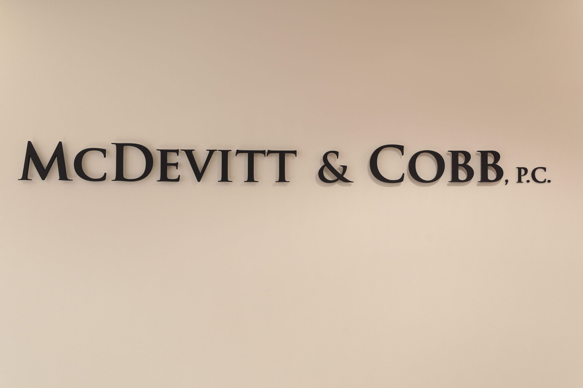 A wall sign reads "McDevitt & Cobb, P.C." in black capital letters on a plain beige background.