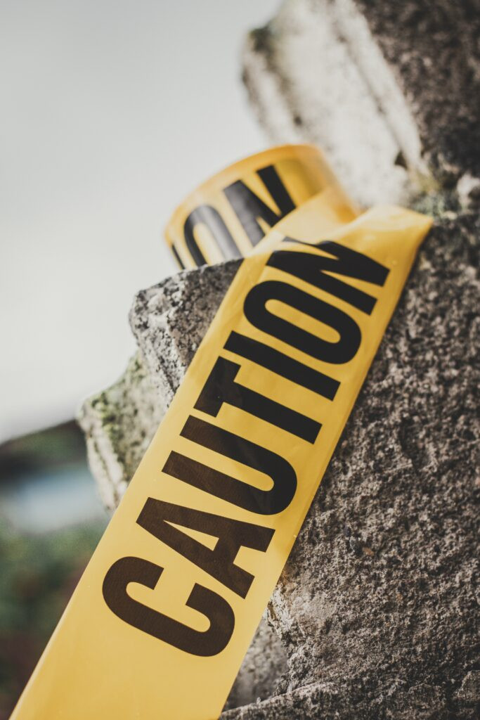 Yellow caution tape marked "CAUTION" is draped over a rough concrete surface outdoors.