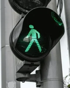 A green pedestrian traffic light signals it's safe to cross, displaying a walking figure with a briefcase.